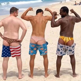 Three friends flexing on the beach in Cheeky Swim Trunks